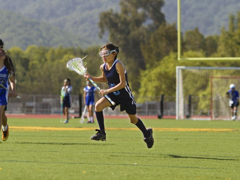 A young girl runs on lacrosse field