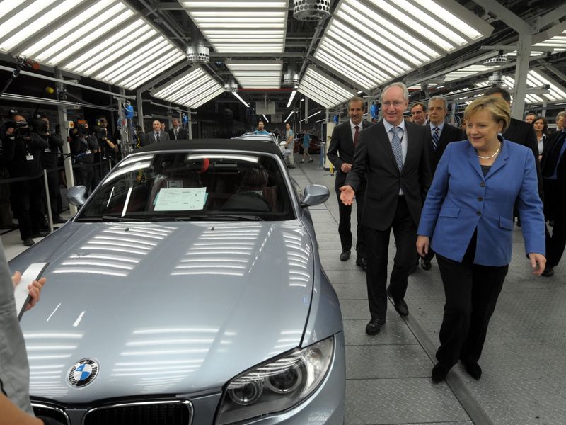 Angela Merkel and other people surveying BMW car