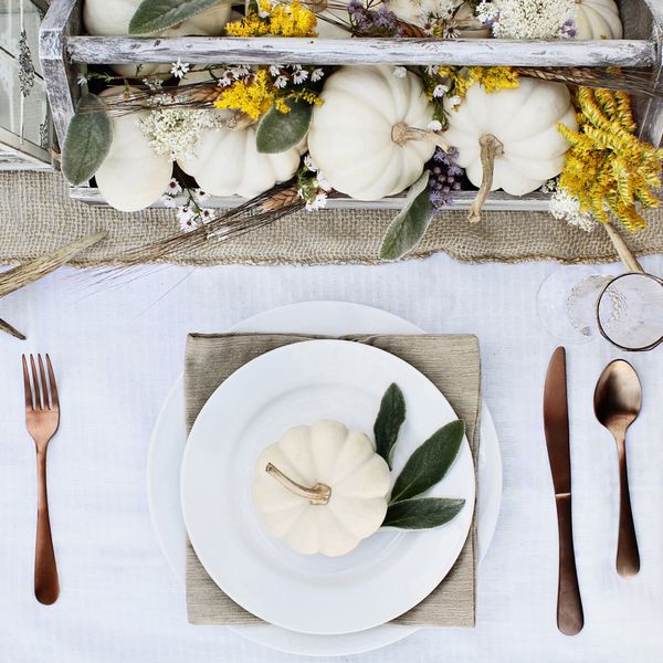 Reserved farmhouse style Thanksgiving or Halloween place setting at a farmhouse table set with mini white pumpkins, Lamb's Ears leaves,  antlers and wildflowers for autumn.