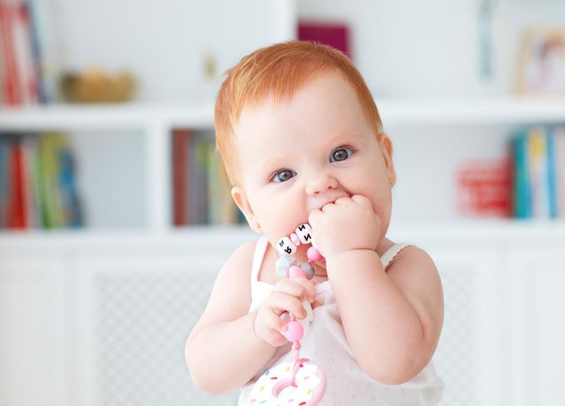 Baby girl biting silicone nibbler toy