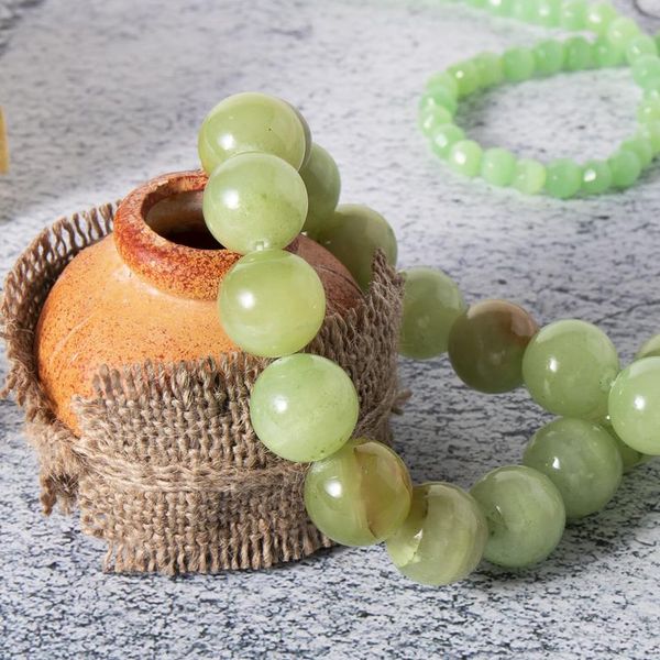 Beautiful beads made from natural green-yellow onyx, agate  (layered chalcedony) stone with jade beads and Baltic amber jewelry on a gray surface. Retro composition.