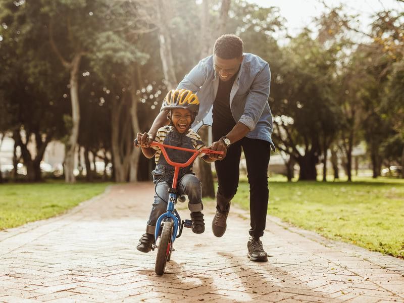 Boy learning to ride a bike with his father