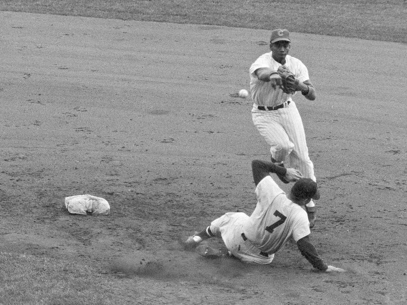 Chicago Cubs shortstop Ernie Banks leaps off ground and throws