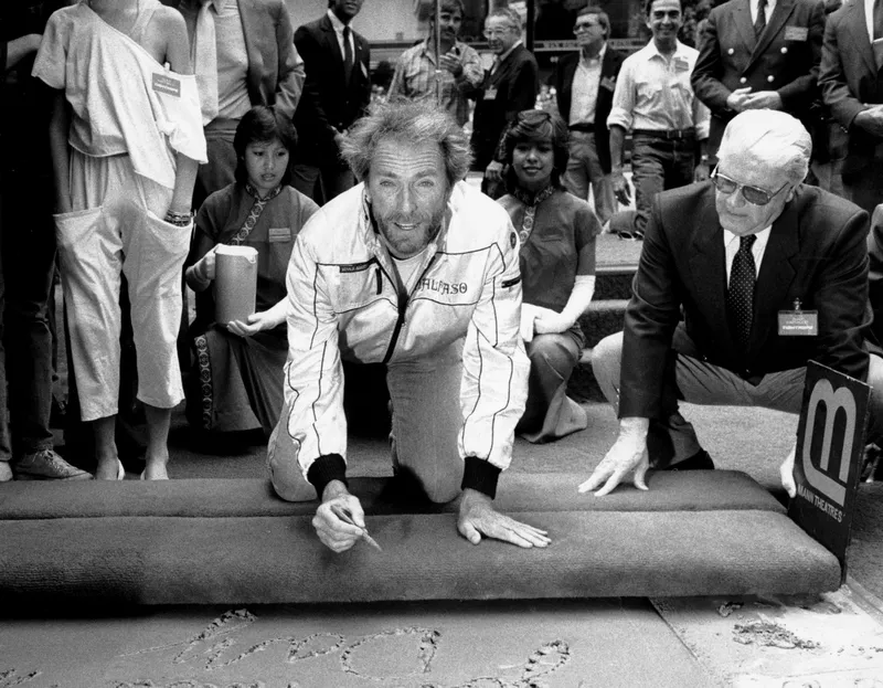 Clint Eastwood pauses as he signs his name into immortality in the wet concrete in the forecourt of Mann's Chinese Theater in Hollywood, Aug. 21, 1984.
