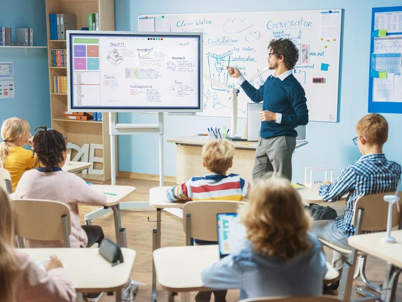 Elementary school science teacher using interactive digital whiteboard in classroom