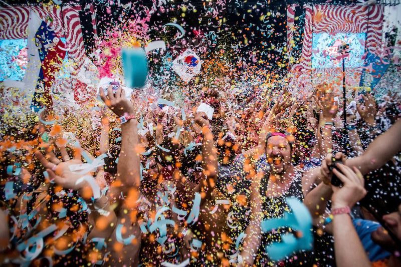 Festival goers throw confetti at each other at 24th Sziget Festival