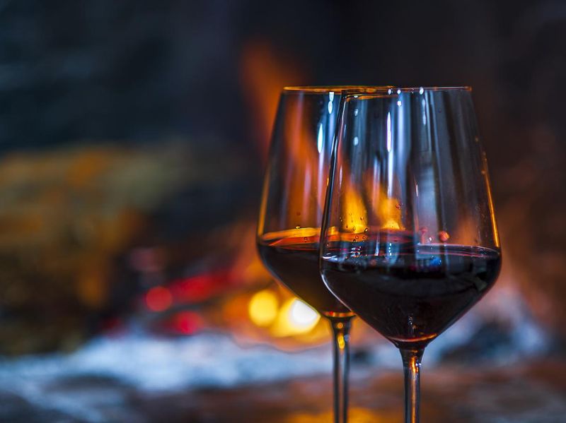 Glasses of red wine in front of fireplace