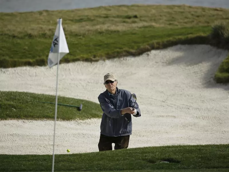 Clint Eastwood tries to hit the ball out of a bunker on the 17th green during the celebrity challenge event of the AT&T Pebble Beach National Pro-Am golf tournament Wednesday, Feb. 6, 2019, in Pebble Beach, California