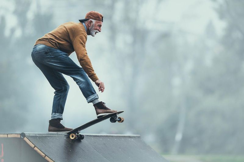 Happy senior man skateboarding on a ramp at the park