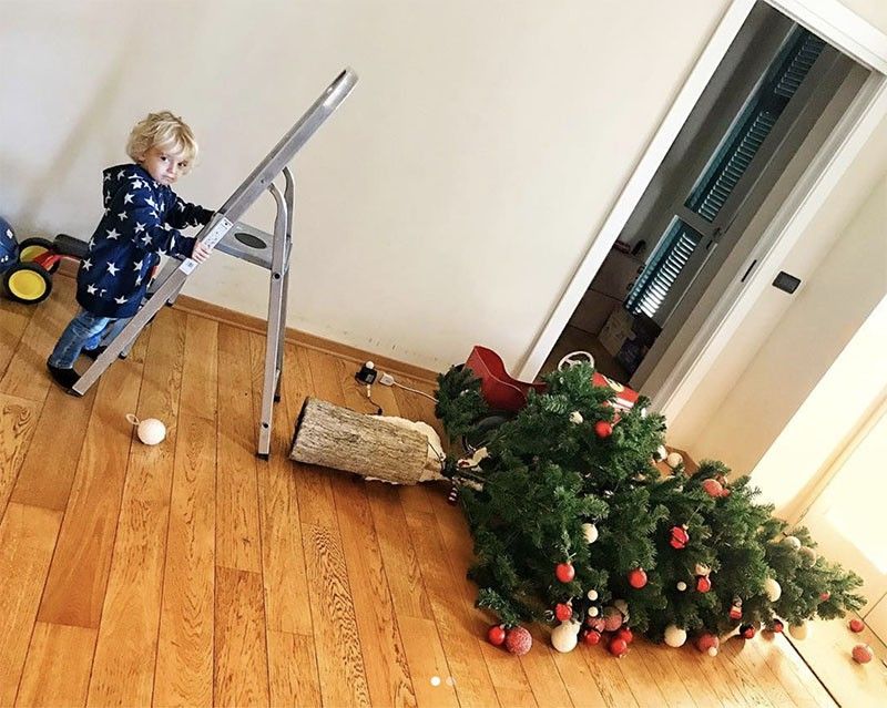 Kid climbing a ladder to fix a fallen Christmas tree