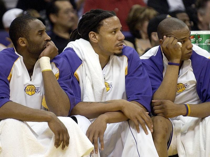 Los Angeles Lakers' Kobe Bryant, Brian Grant, and Caron Bulter watch from bench