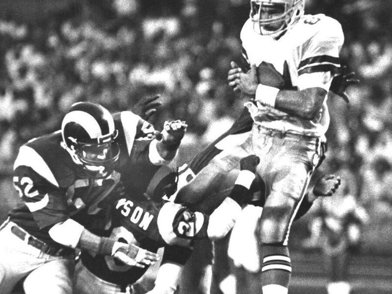Los Angeles Rams linebacker George Andrews and defensive back Johnnie Johnson tackle Dallas Cowboys tight end Doug Cosbie