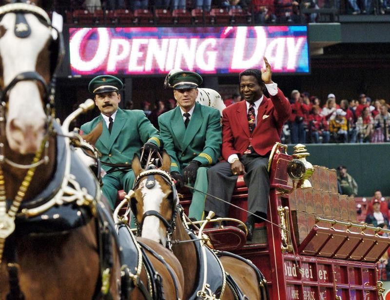 Lou Brock waves to crowd riding on Budweiser Clydesdales
