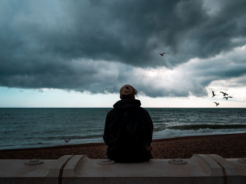 man looking at the sea and storm clouds