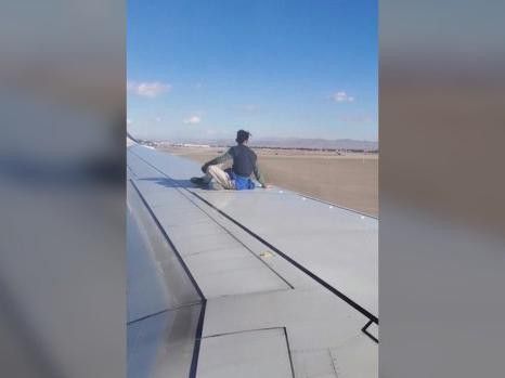 Man sitting on wing of airplane
