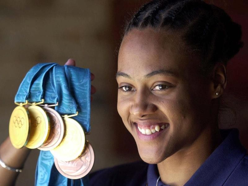 Marion Jones holding up her five Olympic medals