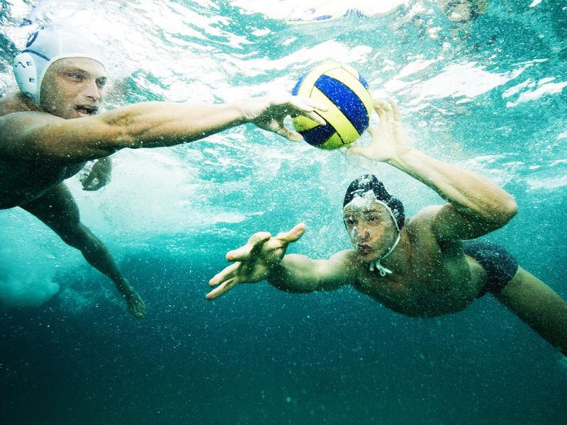 Men fighting for ball under water