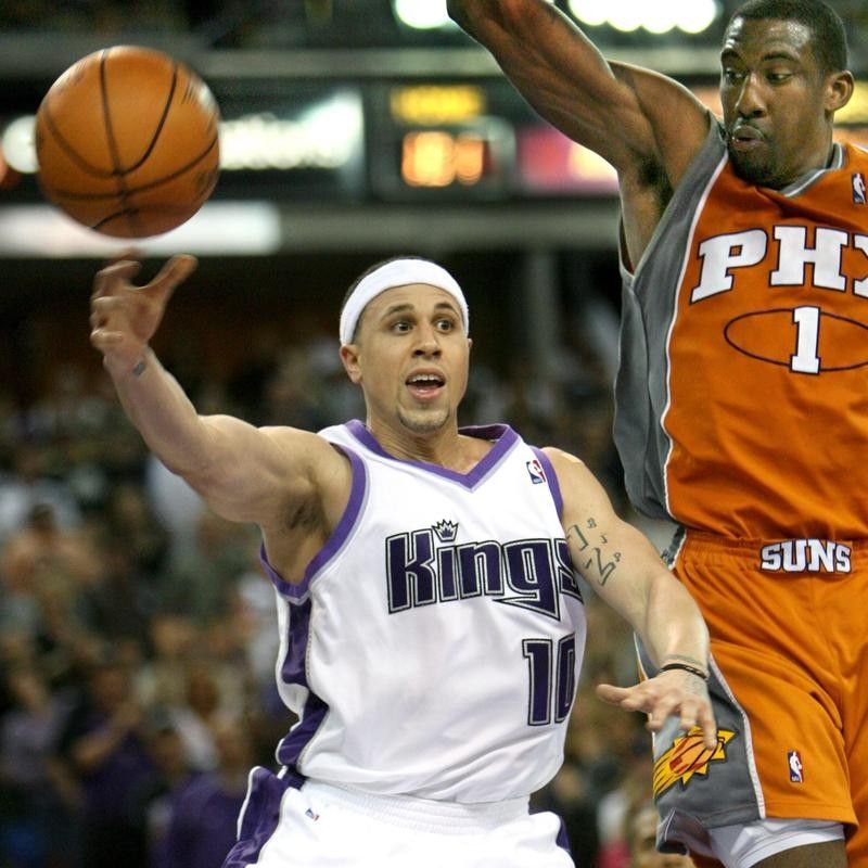 Mike Bibby passes around Amare Stoudemire of the Phoenix Suns