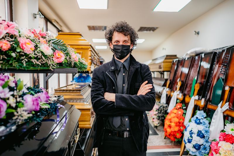 Mortician standing in aisle of coffins