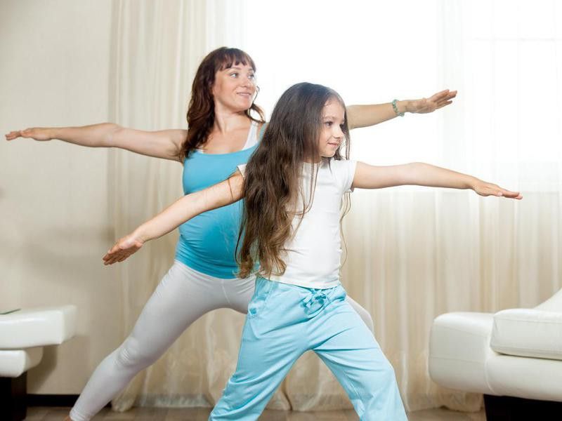 Mother and daughter doing warrior 2 pose