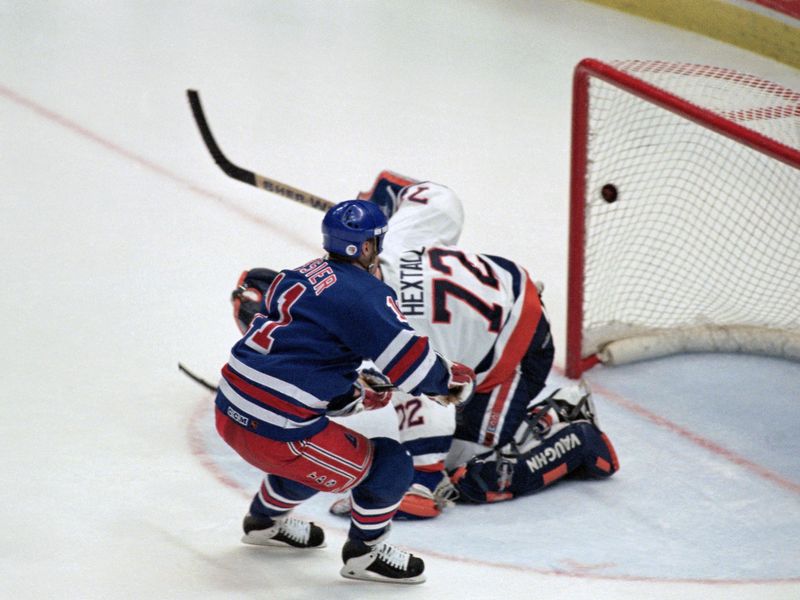 New York Rangers' Mark Messier sends puck over New York Islanders goalie Ron Hextall