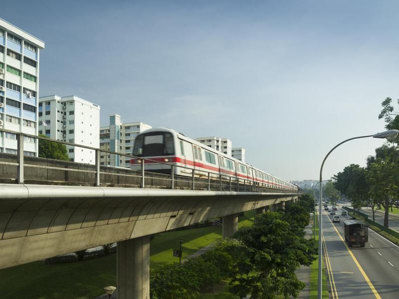 The MRT train on overpass tracks next to buildings and road