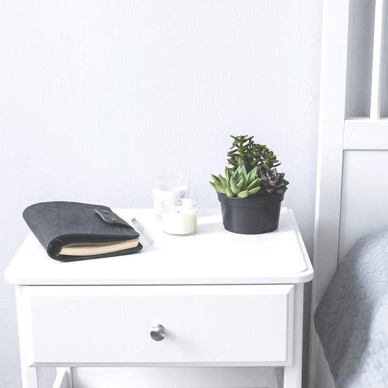 Tiny succulents, candles and black notebook on bedside table