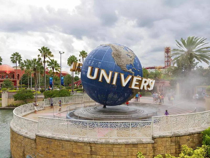 Είσοδος στο τμήμα Universal Studios στο θέρετρο του Ορλάντο, με το ορόσημο σήμα της υδρογείου σε πρώτο πλάνο και τους επισκέπτες γύρω του.