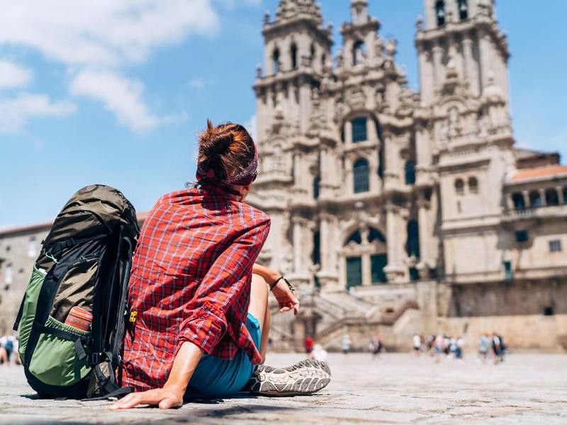 Woman backpacker siting on the Obradeiro square (plaza) in Santiago de Compostela