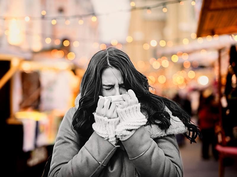 Woman blowing nose while standing in the street