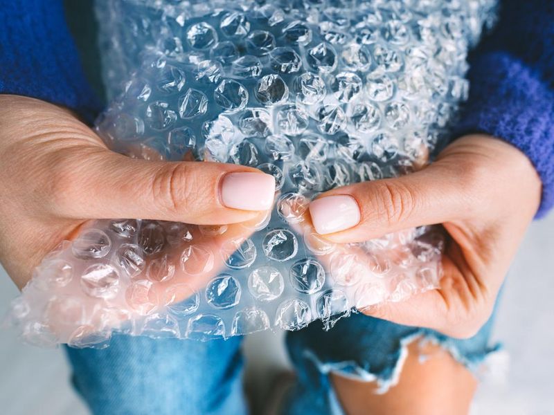 Woman hands squeezing or popping bubbles in bubble wrap