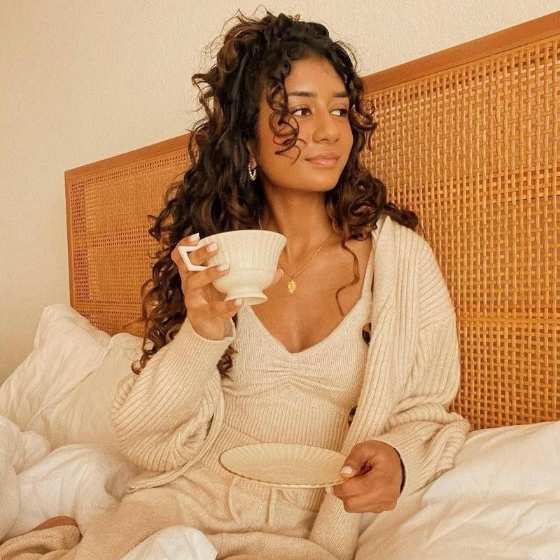 Woman in bed in knit outfit with tea