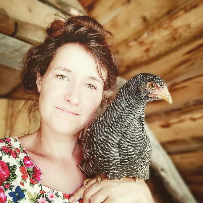 Woman with pet chicken inside a barn
