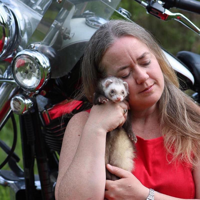Woman with pet ferret and motorcycle
