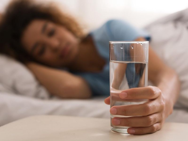 Woman's hand taking glass of water in the morning, hangover cure idea
