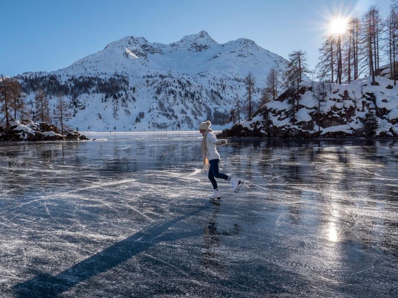 Young woman ice skating on frozen lake at sunset