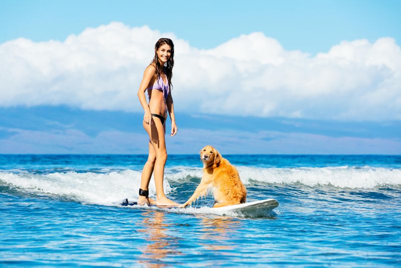 Young woman surfing with her dog